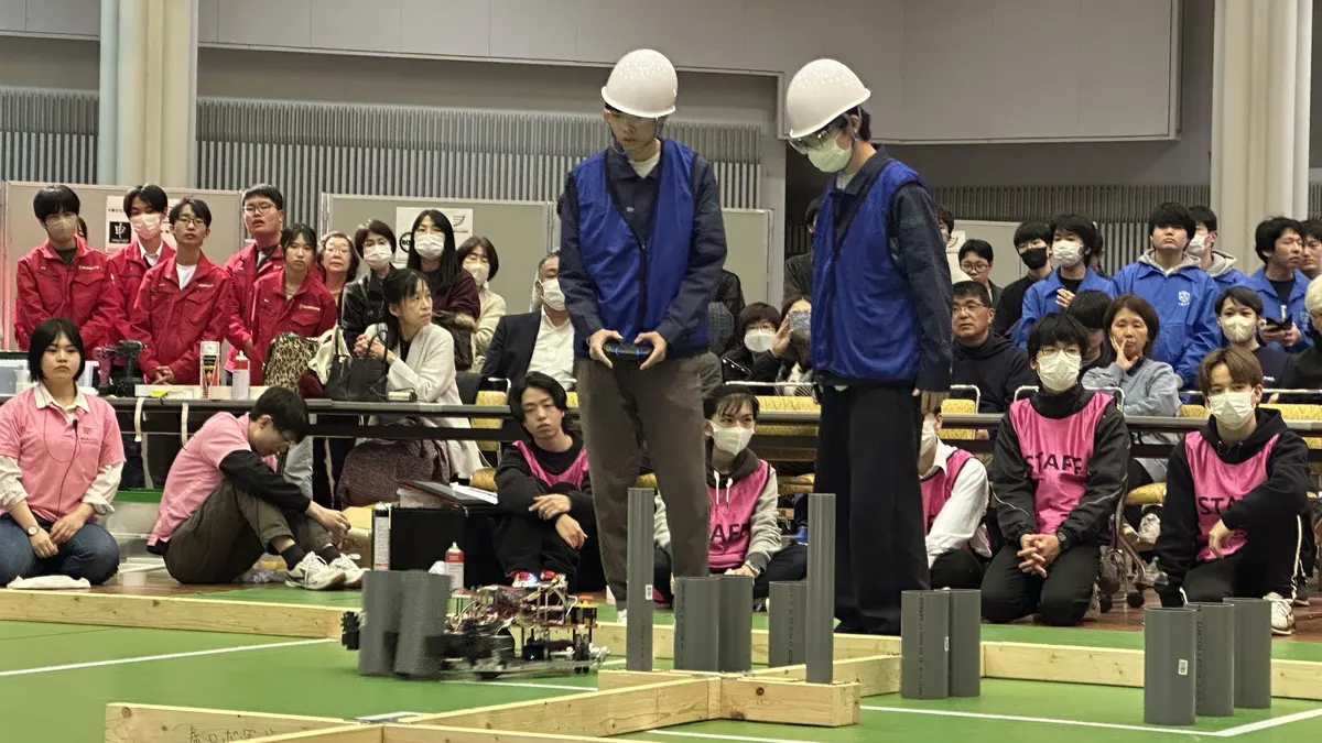 競技フィールドでコントローラーを使ってロボットを操作するメンバー